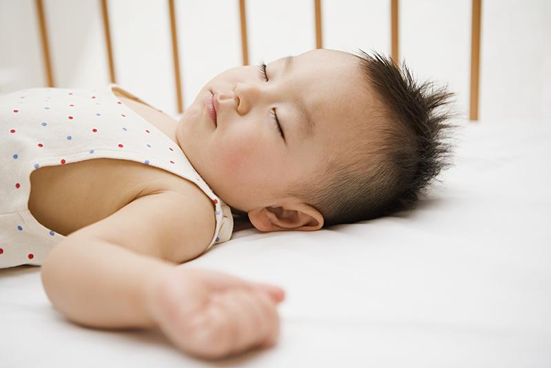 Baby sleeping on back in empty crib