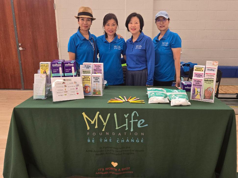 The My Life Foundation Team standing behind a table, filled with promtional material