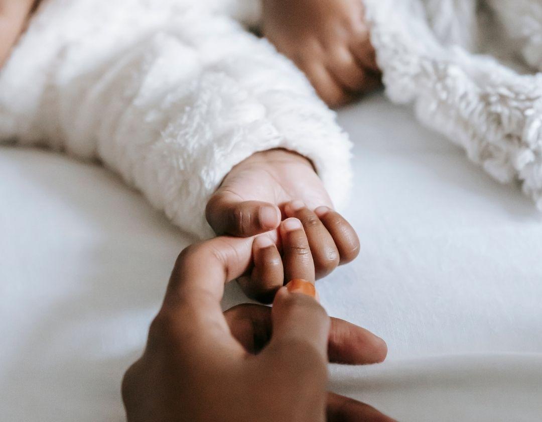 Adult hand holding a baby hand